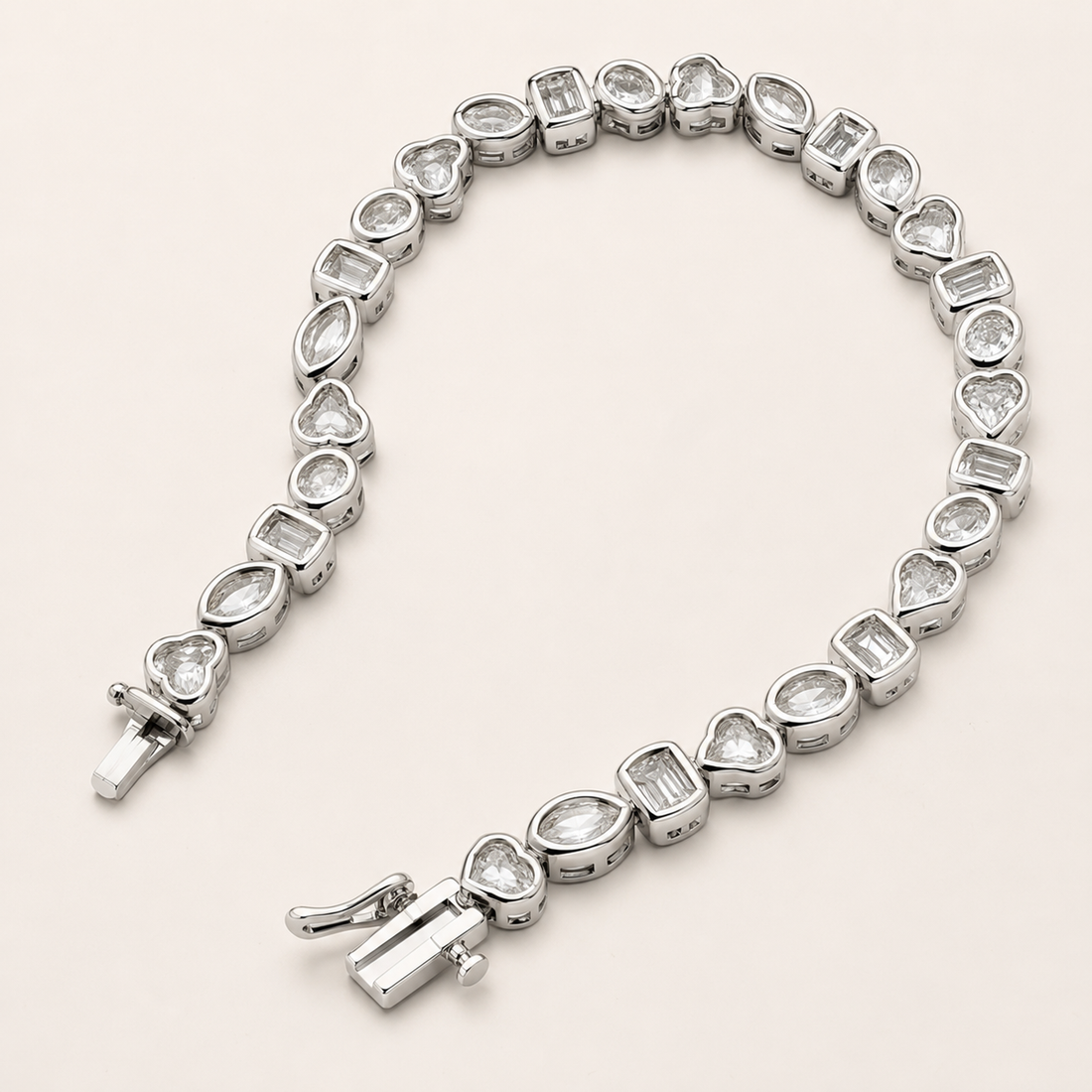 A silver-toned tennis bracelet featuring a continuous row of clear heart-shaped and marquise-cut gemstones in bezel settings, displayed on a light beige background.