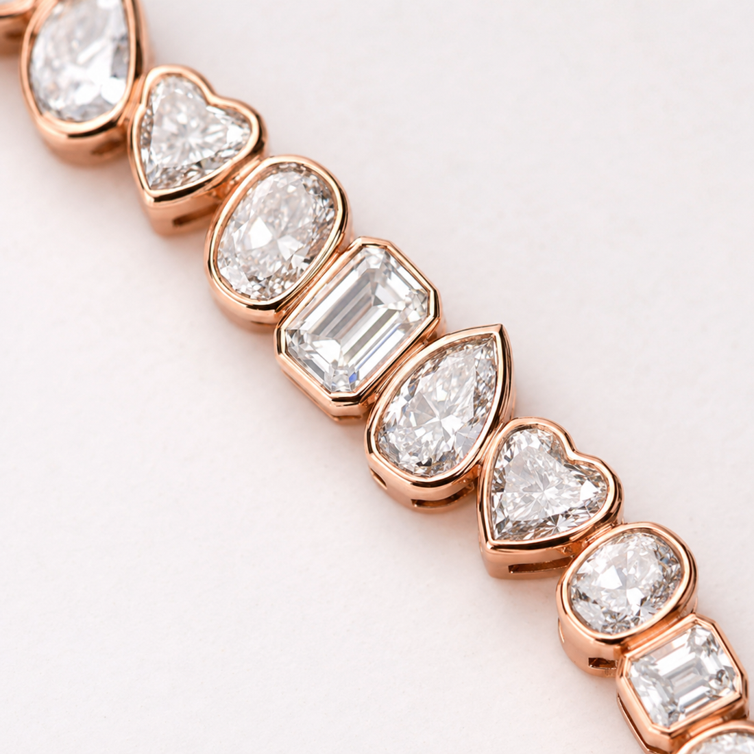 A close-up of a rose gold bracelet featuring alternating heart and oval-cut clear gemstones in polished rose gold settings, set against a clean white background.