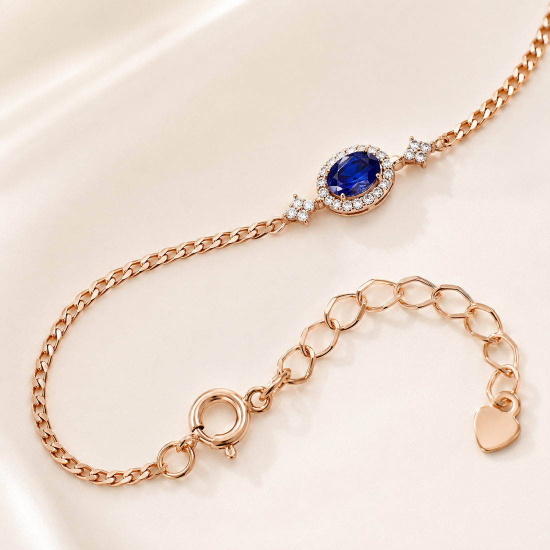 Rose gold chain bracelet featuring an oval blue sapphire center stone surrounded by small clear stones, with star accents and an adjustable link chain extender.