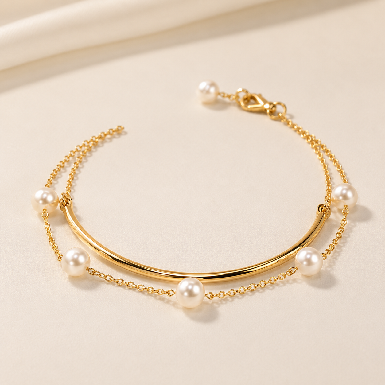 A delicate gold chain bracelet with a curved gold bar and multiple white pearl beads, displayed on a soft beige background.