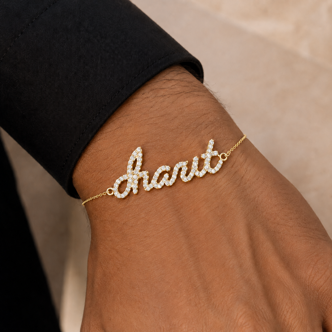 A gold nameplate bracelet with the name charit paved with small clear stones, shown worn on a person's wrist.