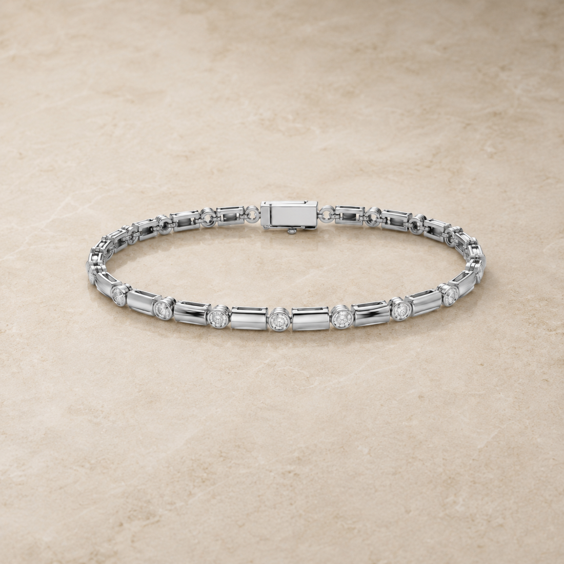 A silver tennis bracelet with baguette and round-cut stones, displayed on a textured beige stone surface.