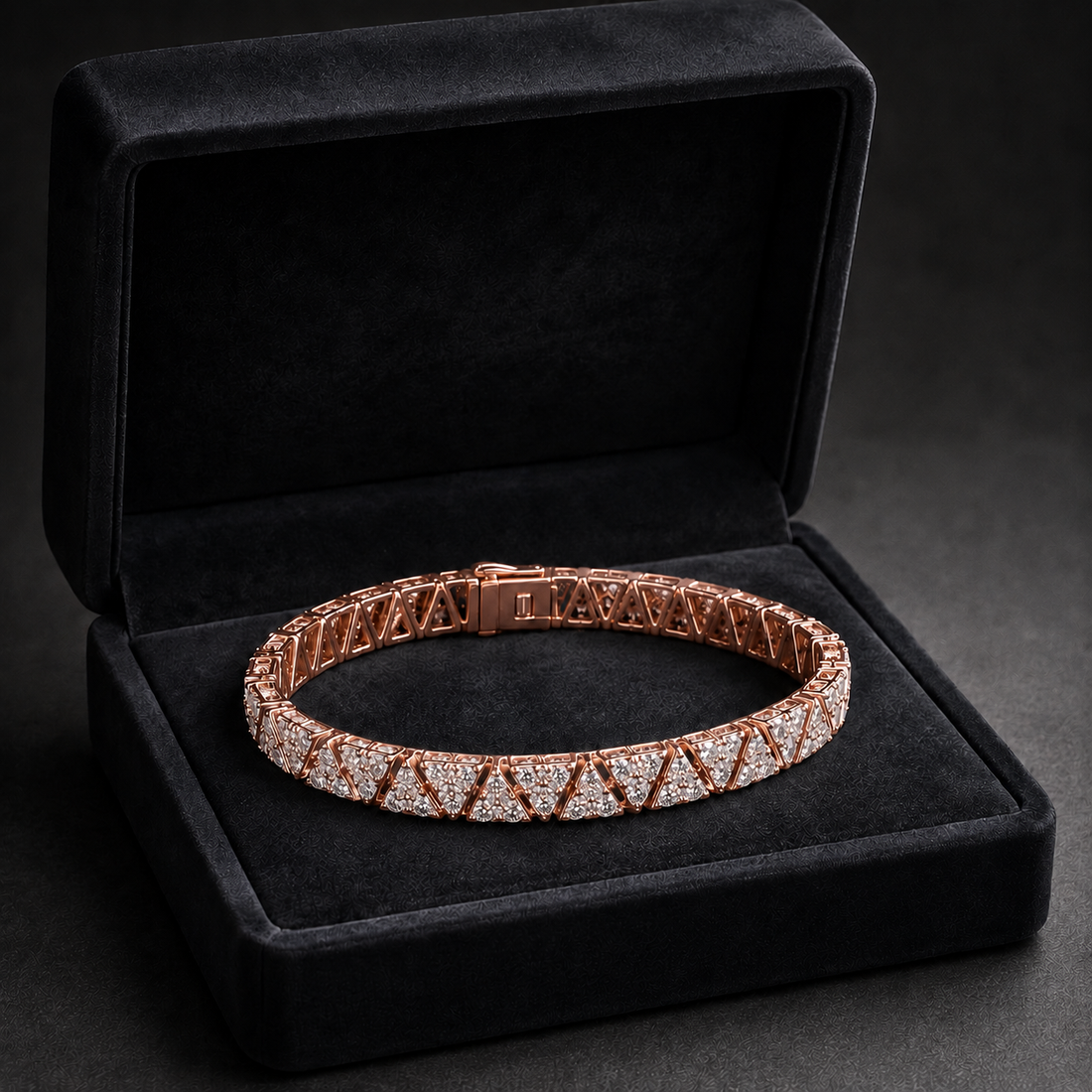 A rose gold tennis bracelet with pavé-set clear stones, displayed inside an open black velvet jewelry box on a dark background.