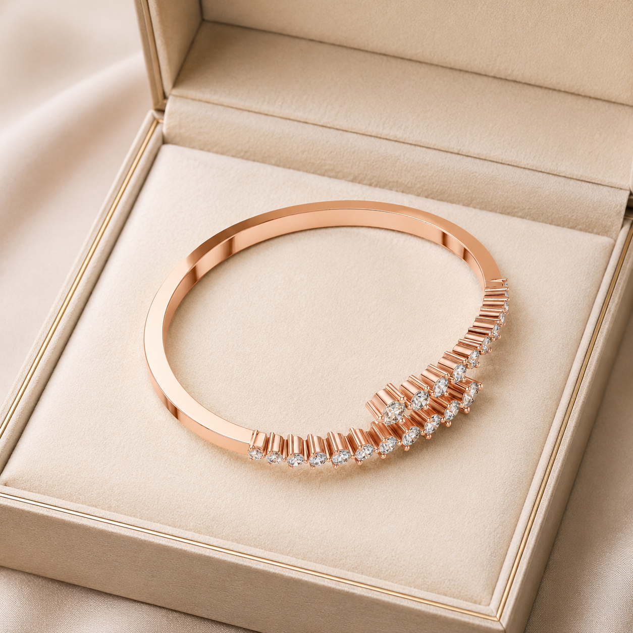 A rose gold bangle bracelet with a curved row of clear marquise-cut gemstones, presented inside a beige jewelry box.