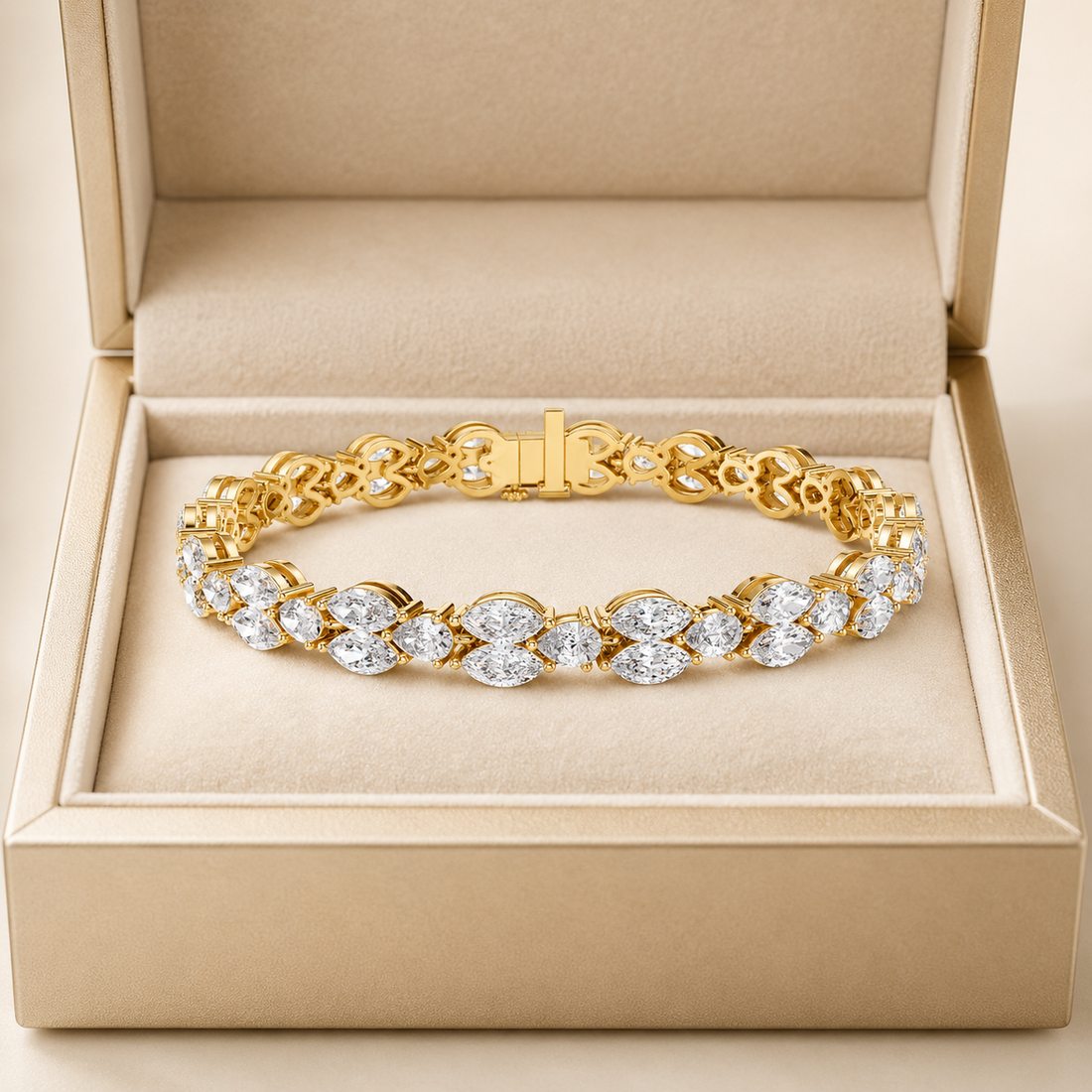 A gold tennis bracelet with marquise and oval-cut clear stones, displayed inside an open beige jewelry box.