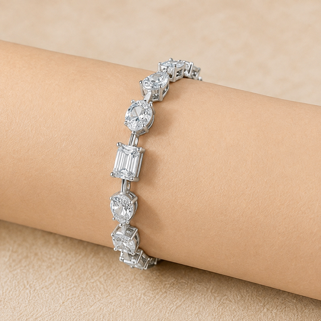 A silver-toned tennis bracelet with clear baguette and round-cut stones, shown worn on a person's wrist against a soft beige background.