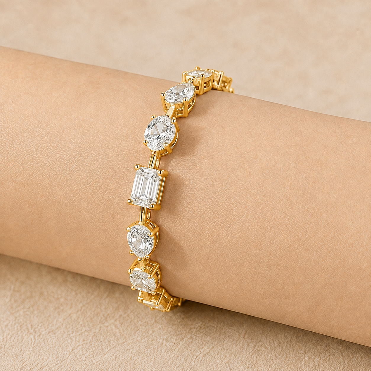 A gold bracelet with clear gemstones in oval and baguette settings, shown worn on a person's wrist against a warm beige background.