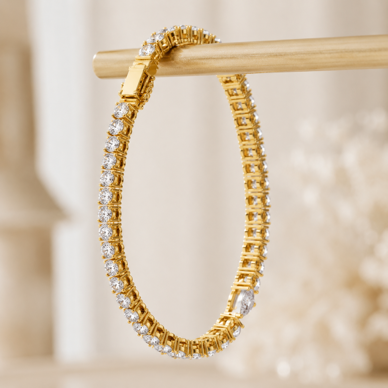 A gold hoop bracelet adorned with clear pavé-set stones, hanging from a wooden display bar against a soft, warm beige background.