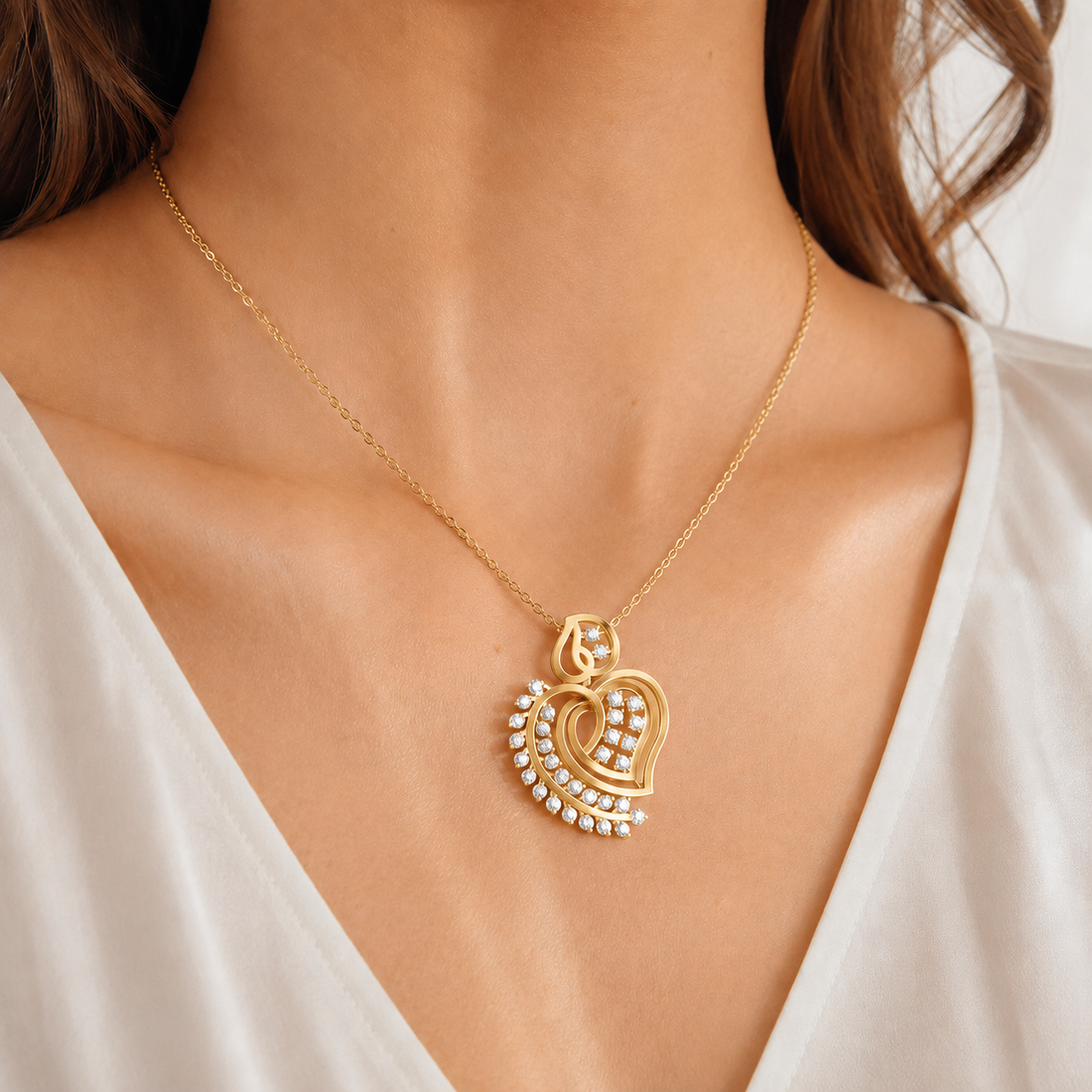 A gold heart-shaped pendant necklace with small white stones, worn on a model's neck over a white V-neck top.