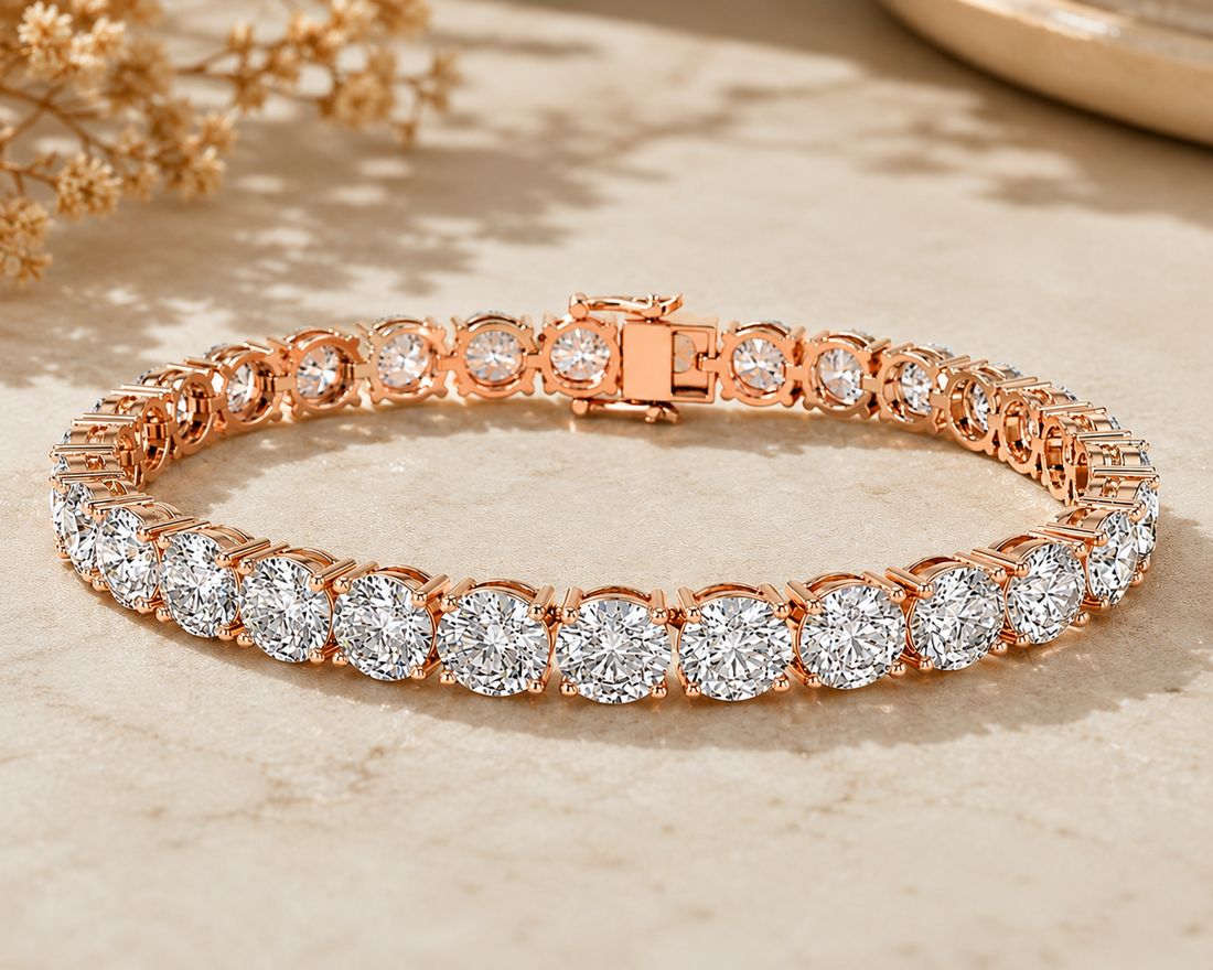 A rose gold tennis bracelet with round-cut clear gemstones, displayed on a light beige textured surface with soft shadows and dried flowers in the background.