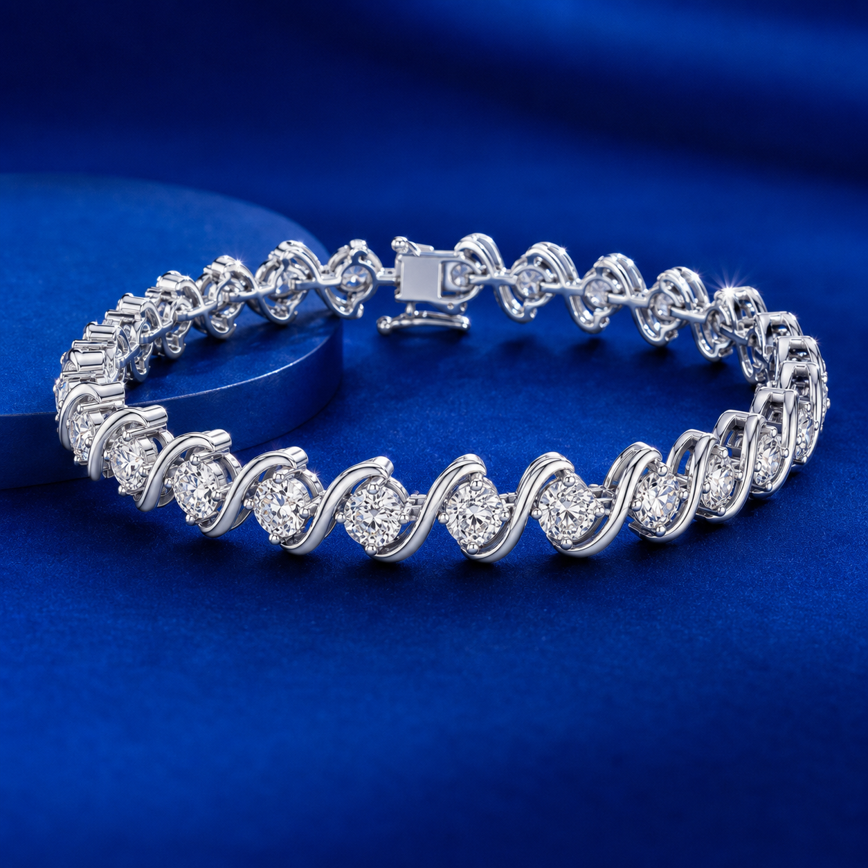 A silver tennis bracelet with round-cut clear stones, displayed on a dark blue circular pedestal against a matching blue background.