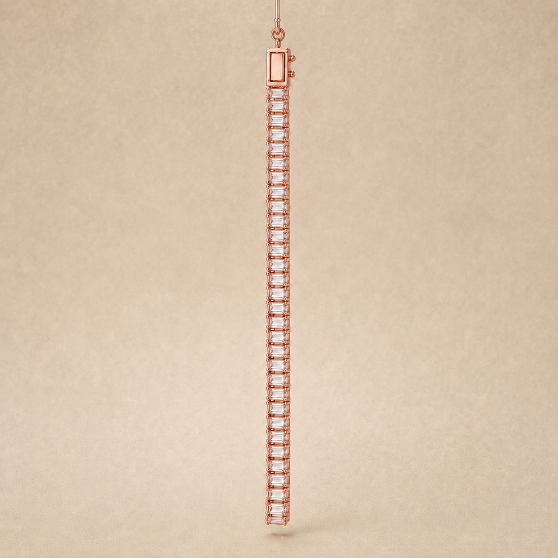 A single long tennis bracelet in rose gold with clear baguette-cut stones, shown hanging against a textured beige background.