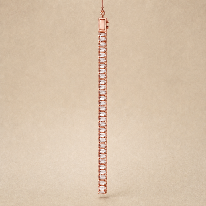 A single long tennis bracelet in rose gold with clear baguette-cut stones, shown hanging against a textured beige background.