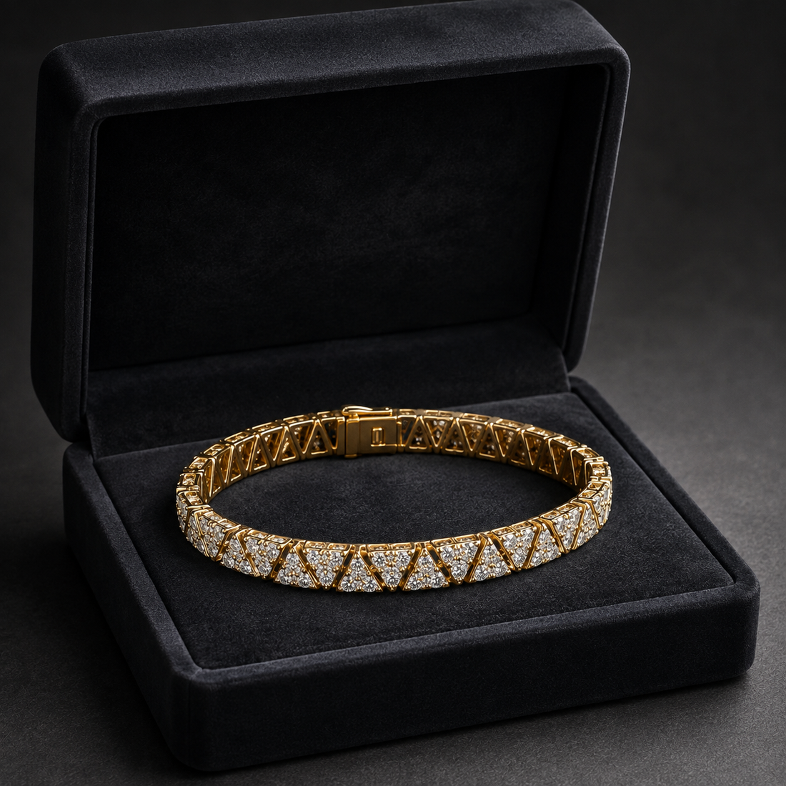 A gold tennis bracelet with pavé-set clear stones, displayed inside an open black velvet jewelry box on a dark gray background.