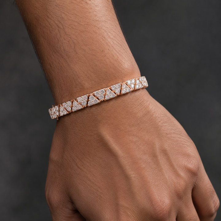 A close-up of a person's wrist and hand wearing a geometric diamond bracelet in rose gold.