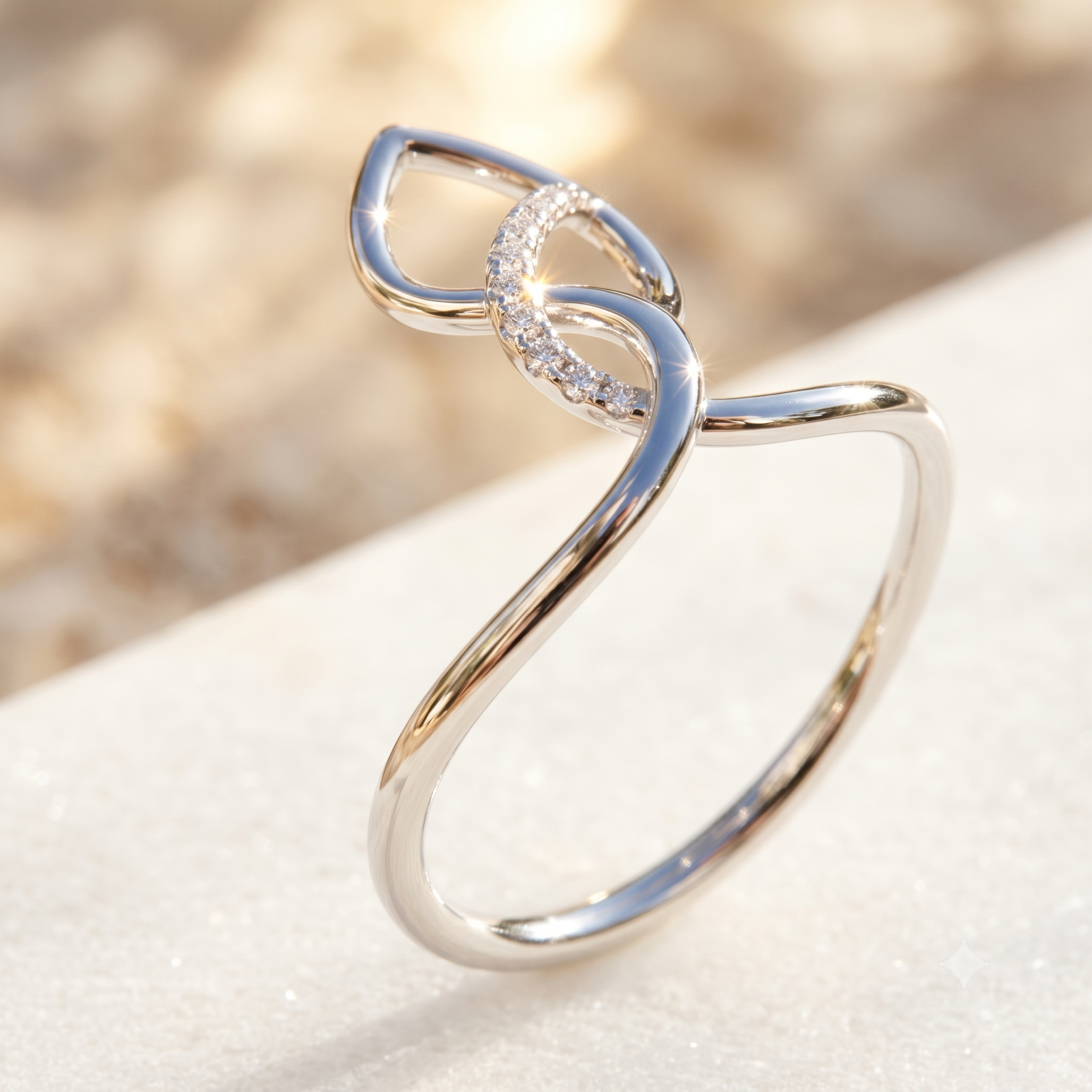 A polished silver ring with an abstract, flowing knot-like design and a small cluster of clear stones, displayed on a light textured surface with a soft-focus beige background.