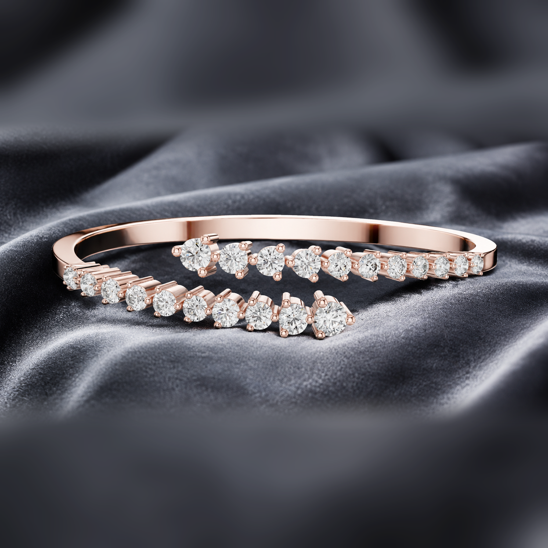 A rose gold bangle bracelet with a row of sparkling clear gemstones, displayed on a dark gray satin fabric background.